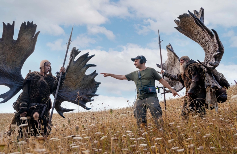 Production member standing inbetween two characters in Lord of the Rings: Rings of Power season one