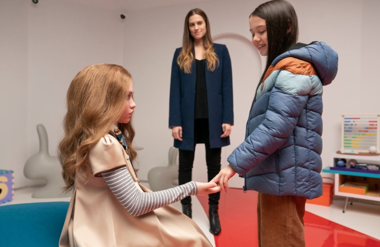 Allison Williams looks at doll and Violet McGraw on set of M3gan film