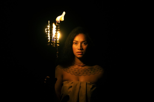Woman holding flaming torch in darkness